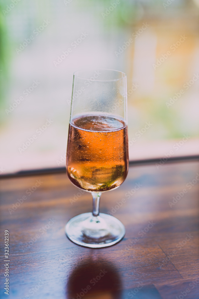 glass of chilled rose wine on wooden table next to window light with backyard bokeh glass of chilled rose wine on wooden table next to window light with backyard bokeh