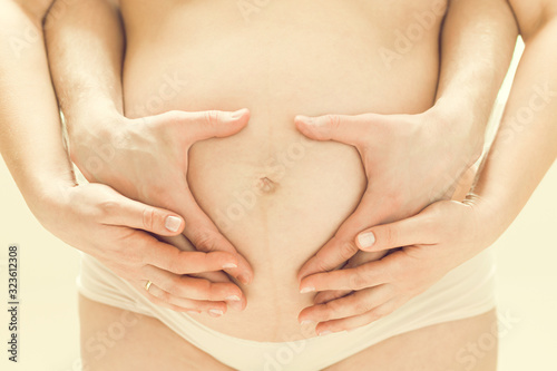 Pregnant woman making heart shape with her hands and men's hands