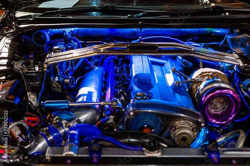 The sports car engine is illuminated with blue neon lights. © ako-photography
