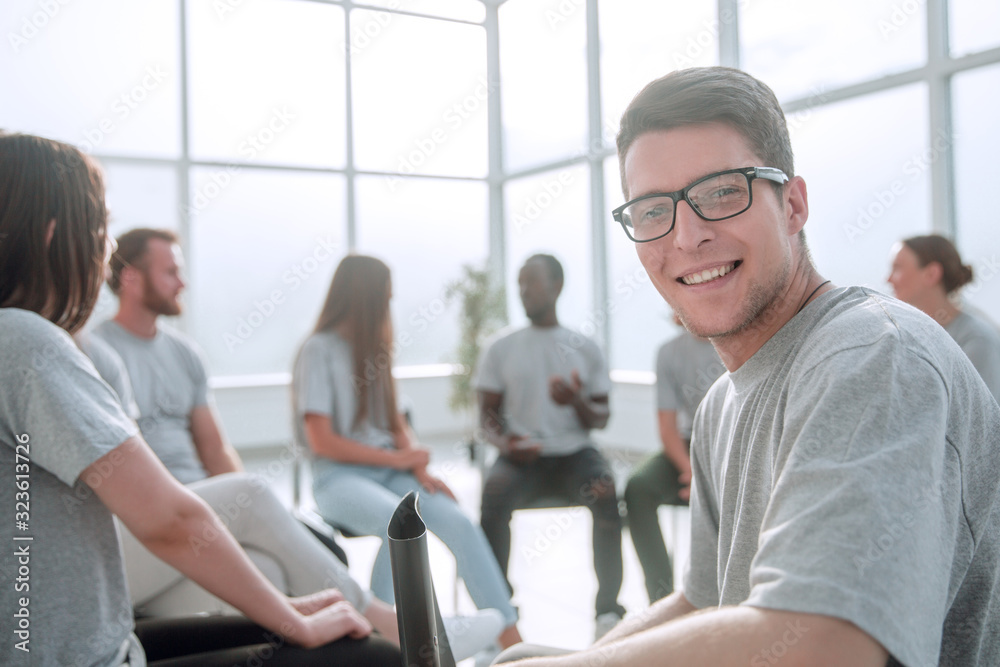 smiling young man sitting in a circle of like-minded people smiling young man sitting in a circle of like-minded people