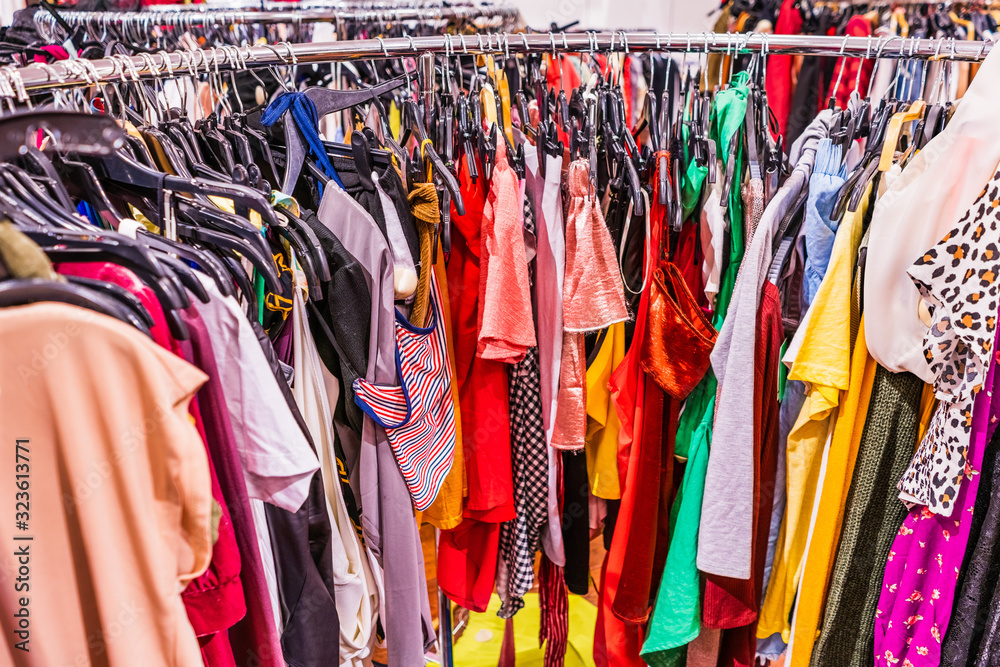 Crowded clearance section in a clothing store, with various colorful garments placed tightly on racks in no particular order; fast fashion concept