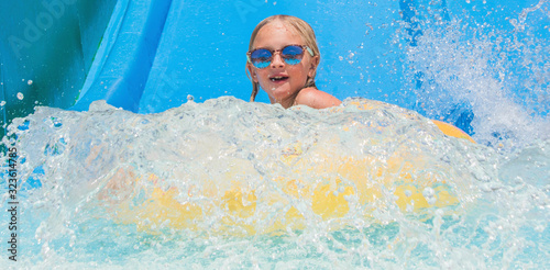 Child on water slide at aquapark. Summer holiday.