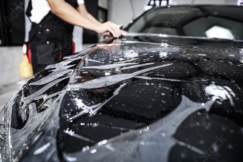 Fototapeta Naklejka Na Ścianę i Meble -  Close up of paint protection film installation on front bumper of modern luxury car. PPF is polyurethane film applied to car surface to protect the paint from stone chips, bug splatter, and abrasion
