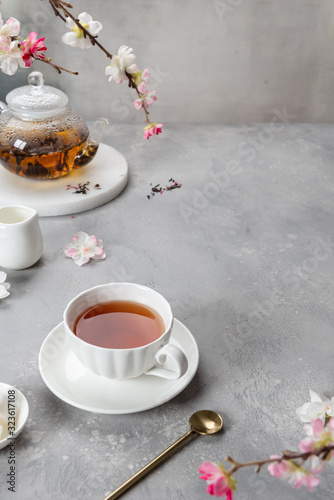 Fragrant tea in a cup and teapot on gray background. Place for your product. Spring tea party. Cafe, reastaurant menu, poster, greeting card, advertising concept. Copy space photo