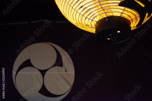 Japanese paper lantern lit and a fabric screen with emblem on background photo