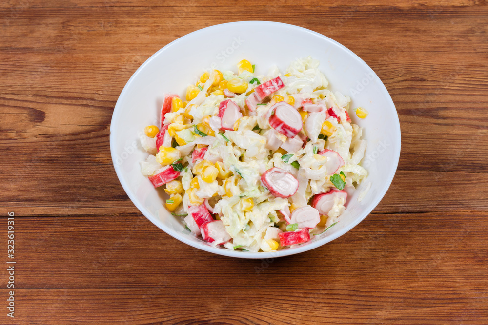 Crab sticks salad with vegetables in bowl on rustic table