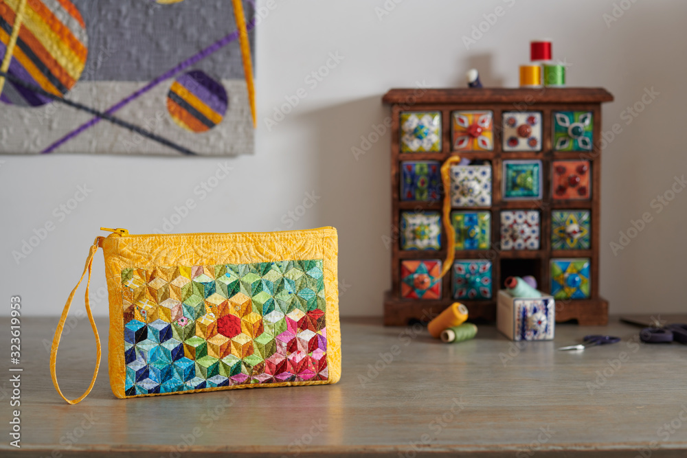 Naklejka premium Patchwork wristlet on the background.wooden mini chest with ceramic drawers