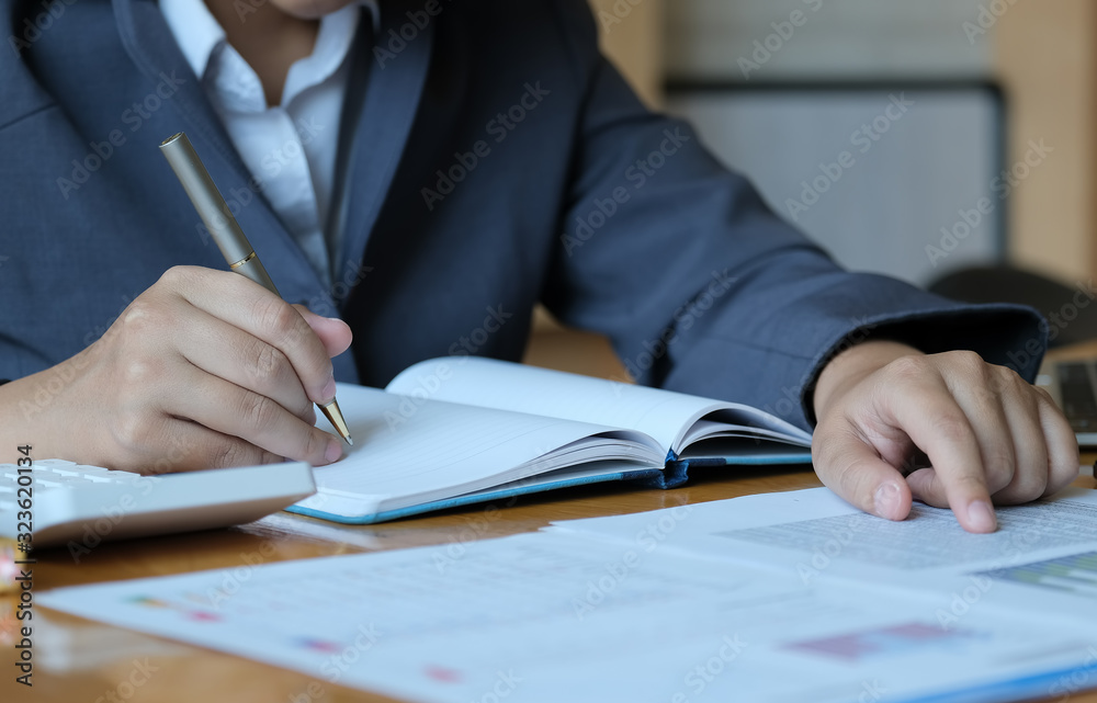 auditor finance concept, businesswoman working on notebook with using laptop, stock market chart and calculator in office her. auditor finance concept, businesswoman working on notebook with using laptop, stock market chart and calculator in office her.