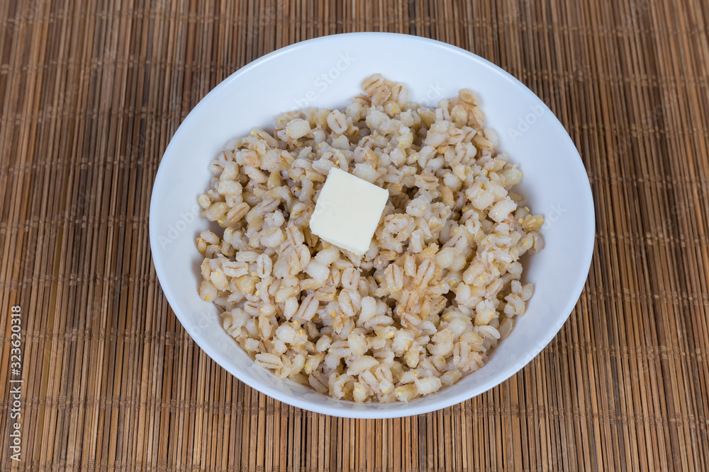 Pearl barley porridge with butter in white bowl Pearl barley porridge with butter in white bowl