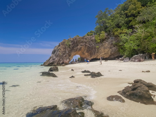 Sea view of many arch rocks floating in blue-green sea with white sand beach  arch rock and green island with blue sky background  Koh Khai island  Satun  southern of Thailand.