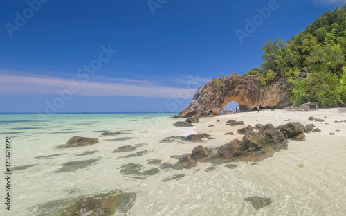 Sea view of many arch rocks floating in blue-green sea with white sand beach, arch rock and green island with blue sky background, Koh Khai island, Satun, southern of Thailand. © Yuttana Joe