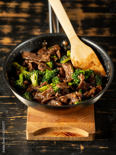 Beef meat and broccoli vegetable cooking in pan close up, selective focus. Traditional food recipe.