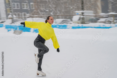 Professional skater on an outdoor ice rink. A woman on knees is preparing a solo program for the competition.