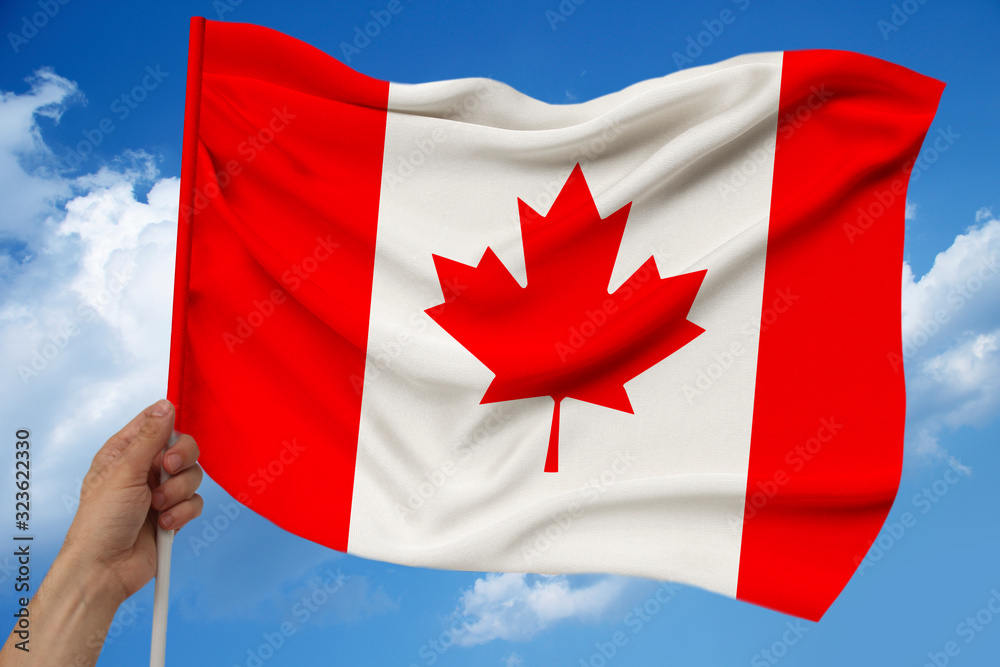 male hand holds against the background of the sky with clouds the national flag of Canada on a luxury satin texture, silk with waves, closeup, copy space, concept of travel, economy, politics male hand holds against the background of the sky with clouds the national flag of Canada on a luxury satin texture, silk with waves, closeup, copy space, concept of travel, economy, politics
