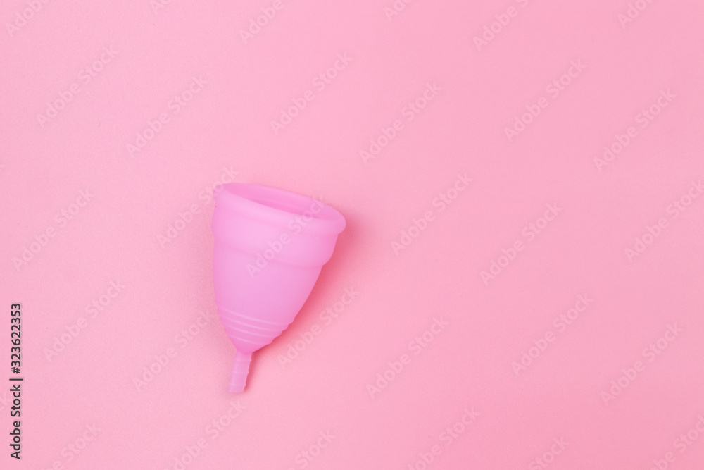Pink reusable silicone menstrual cup on pink background. Top view, copy space. Concept of feminine hygiene, gynecology and health