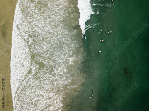Aerial view of surfers catching waves in a beach in San Diego coast.