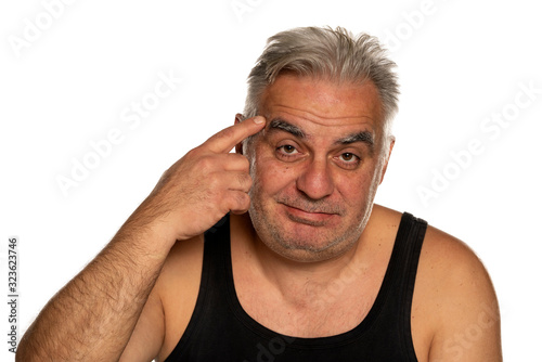  unshaven middle aged man with finger on his forehead