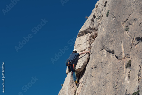 Rock climber in Spanish mountains with blue sky.
