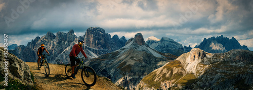 Fototapeta Rowerowa przygoda na świeżym powietrzu w Dolomitach. Jazda na rowerze kobieta i mężczyzna na elektrycznych rowerach górskich w krajobrazie Dolomitów. Tor rowerowy MTB enduro dla par. Aktywność sportowa na świeżym powietrzu.