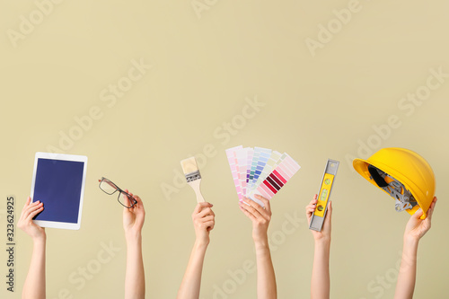 Many hands with architect's supplies and tablet computer on color background