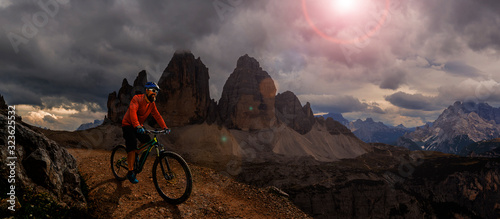 Cycling outdoor adventure. Man cycling on electric bike, rides mountain trail. Man riding on bike in Dolomites mountains landscape. Cycling e-mtb enduro trail track. Outdoor sport activity.