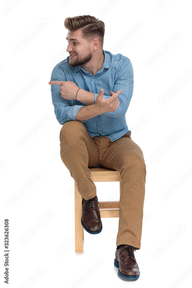 smiling casual man in denim shirt looking to side and pointing smiling casual man in denim shirt looking to side and pointing
