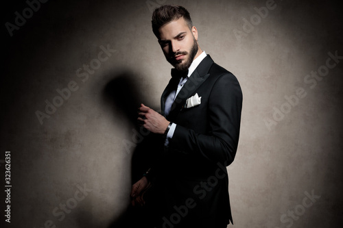 sexy elegant young model in tuxedo holding hand in a fashion pose