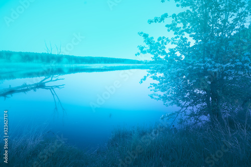 In the evening on the lake in early spring. Tranquil lake in the evening. Rural nature landscape. Soft focus. Blue tones