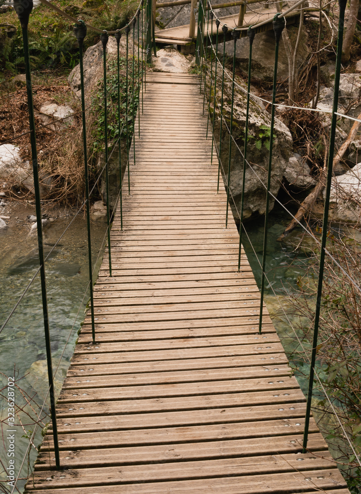 Puente colgante de madera encima de un rio Puente colgante de madera encima de un rio