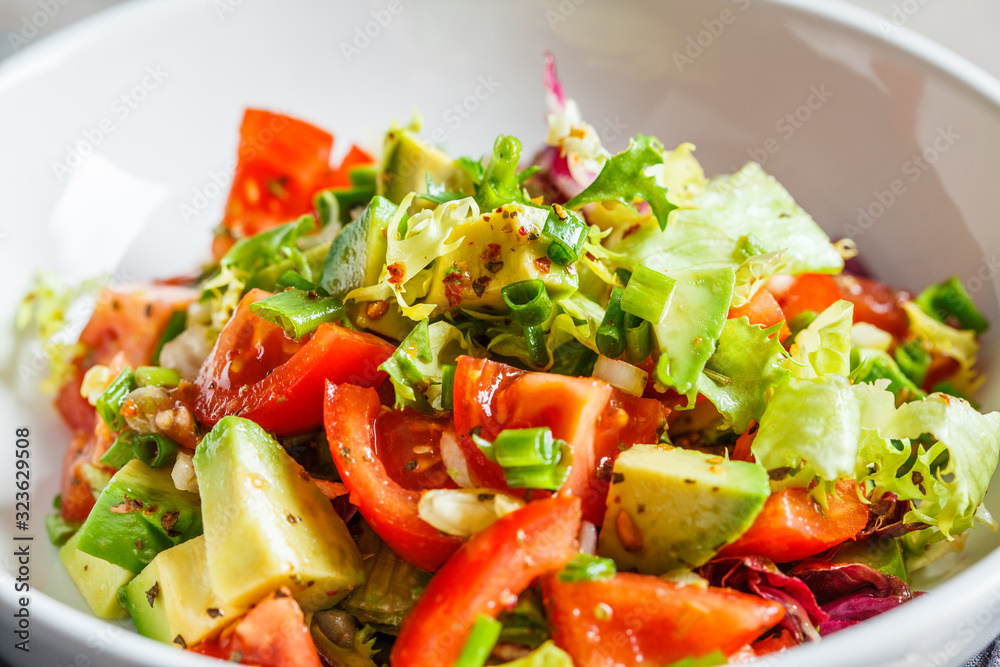 Avocado and tomato salad in white bowl. Vegan food concept. Avocado and tomato salad in white bowl. Vegan food concept.