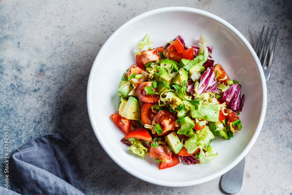 Avocado and tomato salad in white bowl, top view. Vegan food concept. Avocado and tomato salad in white bowl, top view. Vegan food concept.