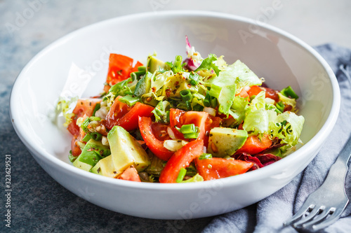 Avocado and tomato salad in white bowl. Vegan food concept.