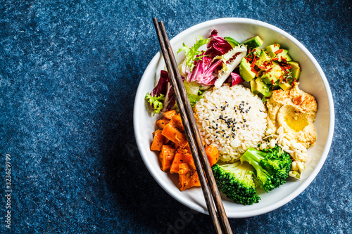 Vegan rice and vegetables salad, top view. Macrobiotic set with rice, hummus, avocado, broccoli and sweet potato.