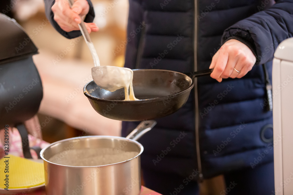 Pancakes are cooked on the street. Pour pancake dough into a pan. Maslenitsa. Pancakes are cooked on the street. Pour pancake dough into a pan. Maslenitsa.