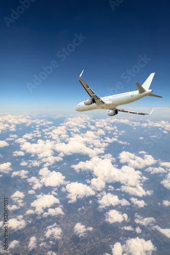 Airplane flying at high altitude over green mountains and sky at sunrise