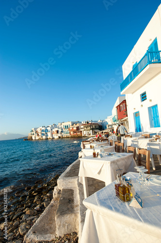 Scenic seaside view of empty tables waiting for diners in Mykonos Town, Greece