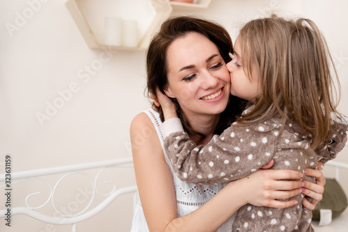 daughter hugs mom and gently kisses her cheek.