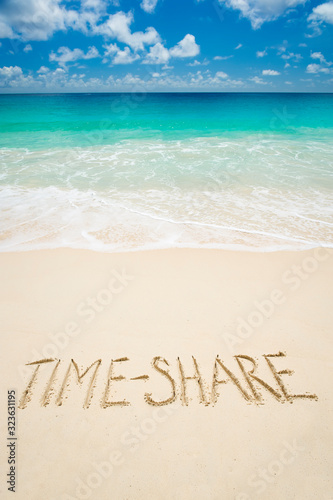 Time Share travel real estate message handwritten on bright tropical beach