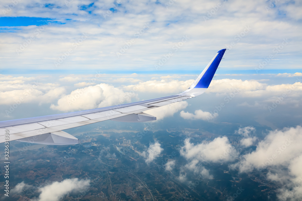 Fototapeta premium Airplane flying at high altitude over green mountains and sky at sunrise