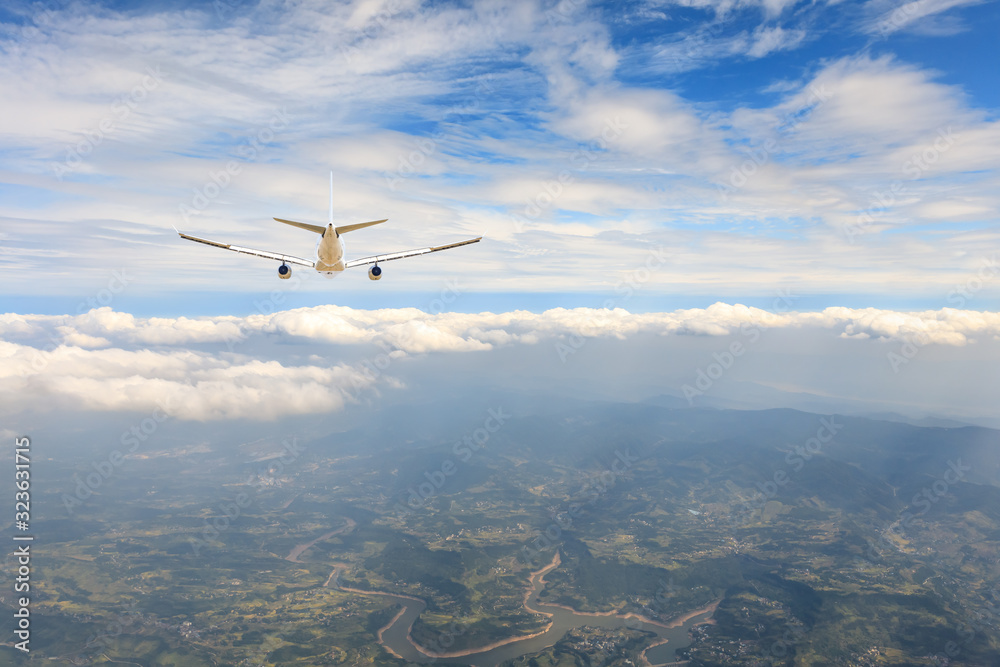 Fototapeta premium Airplane flying at high altitude over green mountains and sky at sunrise