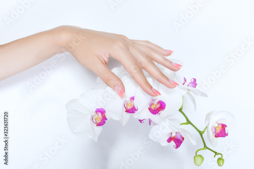 Hand of woman with a beautiful manicure strokes magnolia flowers.