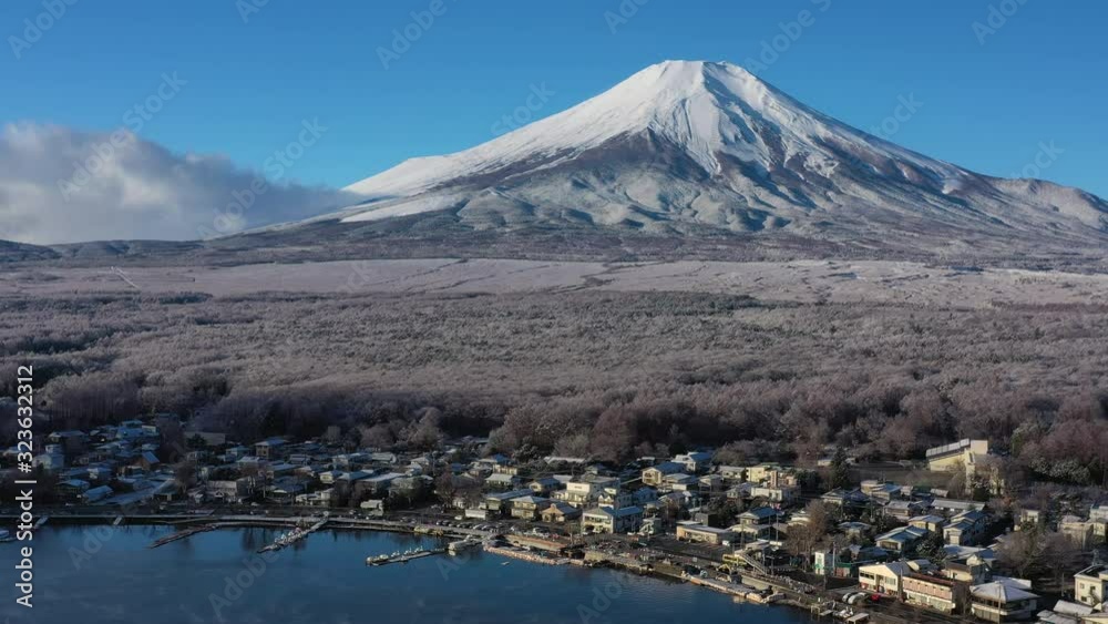 Aerial view of Mount Fuji in winter, iconic snow-capped symbol of Japan, snow covered scenery with freezing fog on trees, lake Yamanaka, clear blue sky - landscape panorama of Japan from above, Asia