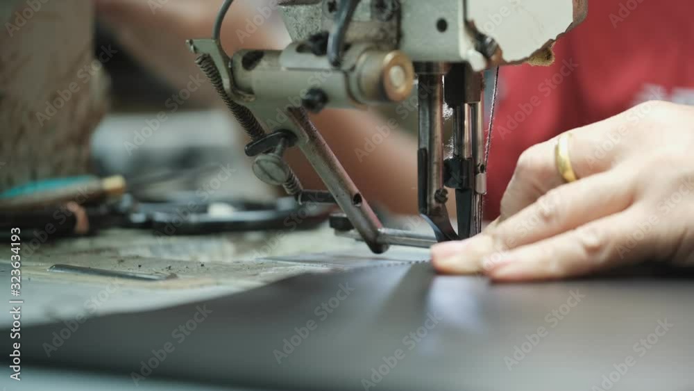 Close-Up Of Tailor Working On Sewing Machine in leather factory background Close-Up Of Tailor Working On Sewing Machine in leather factory background