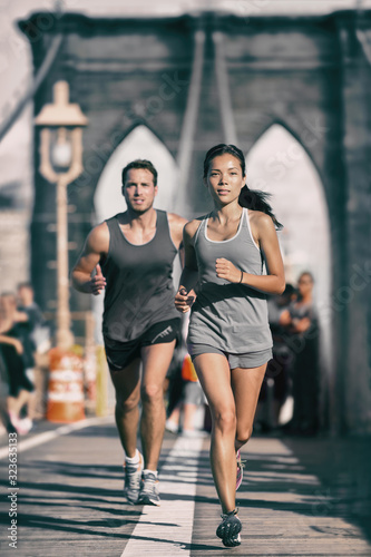Fotografie, Obraz New York city runners athletes training jogging on Brooklyn Bridge for Marathon race, fit couple on outdoor summer run jog