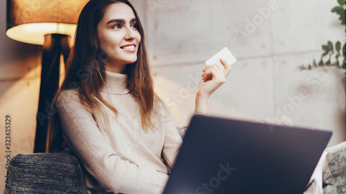 Girl using bank card for buying things online. Retail stores offering bonus cards for customers. Select items in web shop app, transfer money safely using sms code for payment. photo
