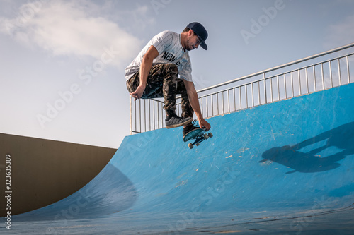 joven skater hace un truco llamado  boneless en la rampa de un parque de patinaje photo