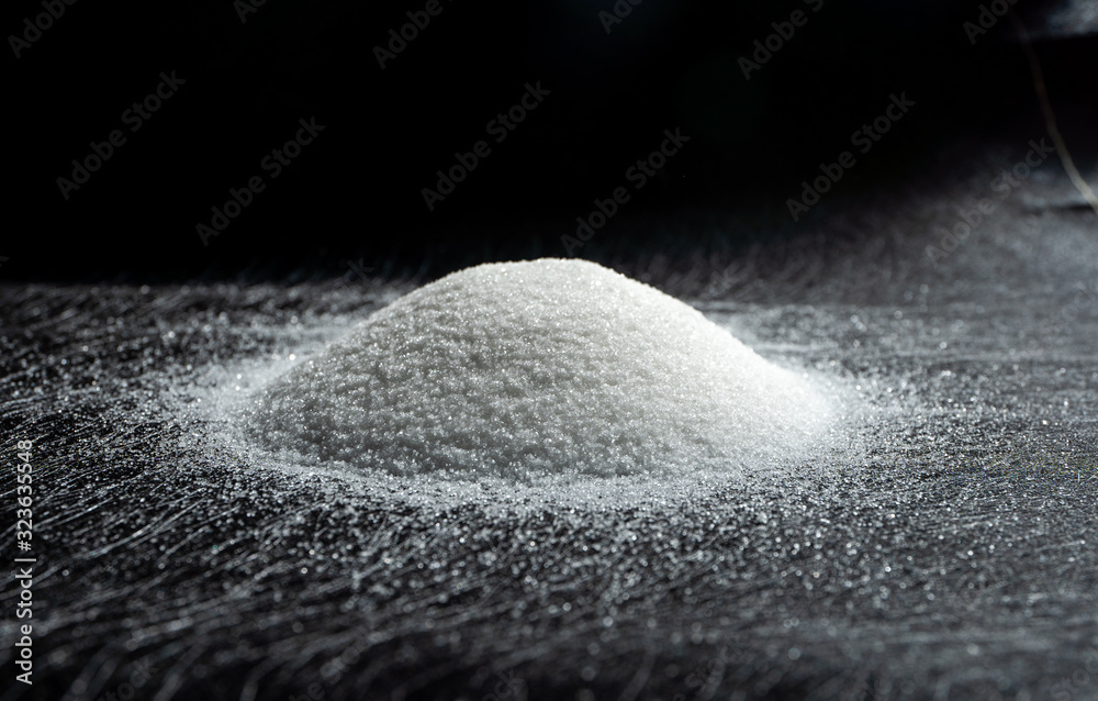 Fototapeta Heap of sugar on a dark background.