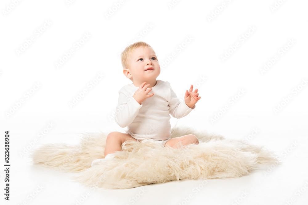 Cute child looking up and sitting on fur on white background Cute child looking up and sitting on fur on white background