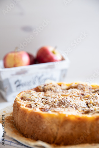 Bratapfelkuchen mit Äpfeln und Mandelblättchen auf hellem weißen Holzgrund