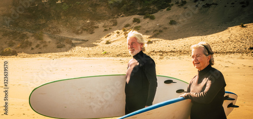 Canvas Print couple of seniors going surfing together - two mature people in the beach with s
